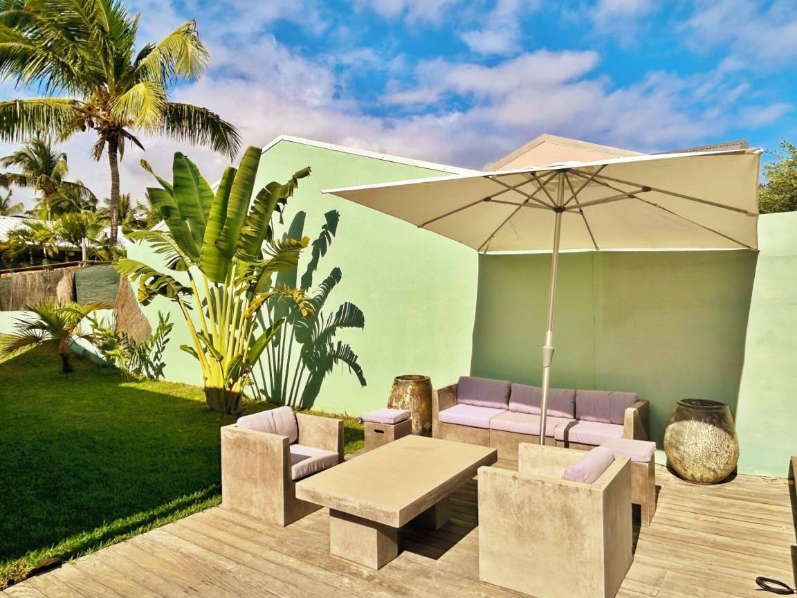 Salon d'extérieur avec parasol au bord du jardin